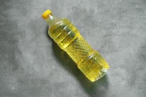 cucinando olio nel un' giallo bottiglia su un' calcestruzzo sfondo foto
