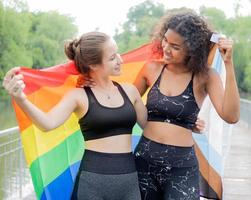 Due lesbica persone amicizia con arcobaleno orgoglio bandiera. allegro gay persona avendo divertimento insieme con uguaglianza rispetto per amore e la libertà stile di vita. diversità di giovane omosessuale coppia, LGBTQ diritti. foto