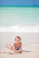 adorabile poco ragazza a bianca spiaggia durante estate vacanza foto