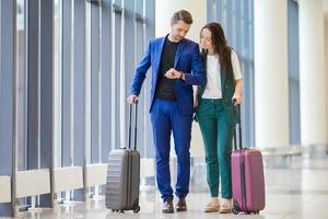 turisti coppia con Bagaglio nel internazionale aeroporto. uomo e donna andando su atterraggio foto