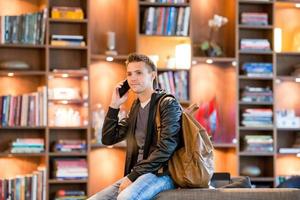 giovane uomo assunzione di smartphone nel libreria foto