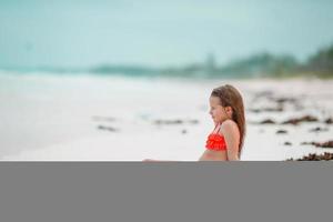 adorabile poco ragazza avere divertimento a superficiale acqua su bianca spiaggia foto