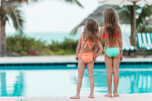 adorabile poco ragazze avendo divertimento nel all'aperto nuoto piscina su estate vacanza foto