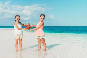 adorabile poco ragazze con stelle marine su bianca vuoto spiaggia foto