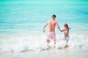 poco ragazza e contento papà avendo divertimento durante spiaggia vacanza foto