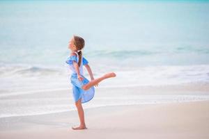 adorabile poco ragazza su il spiaggia. contento ragazza godere estate vacanza sfondo il blu cielo e turchese acqua nel il mare foto