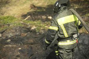 pompiere mette su fuoco. Bagnino versa acqua a partire dal tubo flessibile. foto