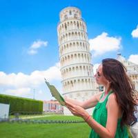 giovane contento ragazza con turistico carta geografica su viaggio per pisa. turista in viaggio visitare il pendente Torre di pisa. foto