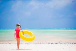 adorabile ragazza con gonfiabile gomma da cancellare cerchio andando per nuotare nel il mare foto