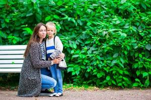 contento madre e adorabile poco ragazza godendo caldo tempo metereologico a bellissimo parco foto