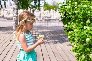 poco adorabile ragazza vicino bianca fiori nel il giardino foto