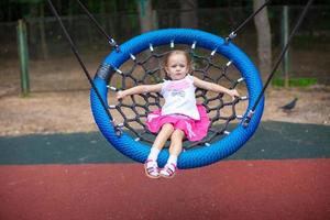 poco ragazza su swing a un divertimento parco foto