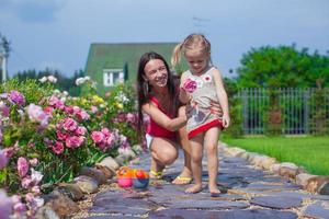 giovane madre con sua carino figlia avere divertimento nel il giardino estate tempo foto