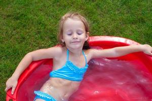 affascinante poco ragazza godendo sua vacanza nel il piscina all'aperto foto