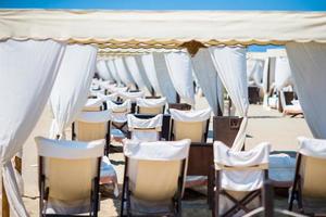 di legno lettini nel davanti di un' turchese mare nel il sera luce. lettini nel famoso italiano sabbia spiaggia a forte dei marmi foto