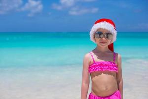 poco carino ragazza nel rosso Santa cappello su tropicale spiaggia foto