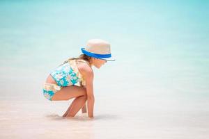 poco ragazza a tropicale bianca spiaggia fabbricazione sabbia castello foto