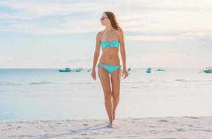 donna posa su il spiaggia godendo estate vacanze guardare a il mare foto