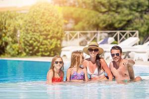 contento famiglia di quattro nel all'aperto nuoto piscina foto