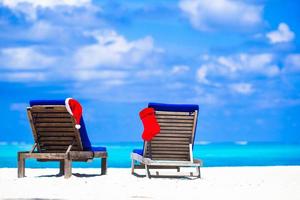 rosso Natale calza e Santa cappello su sedia a tropicale bianca spiaggia foto