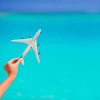 poco bianca aereo modello nel femmina mano sfondo di turchese mare foto