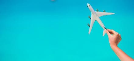 poco bianca aereo modello nel femmina mano sfondo di turchese mare foto