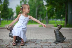 poco ragazza alimentazione il anatre figura nel il parco foto