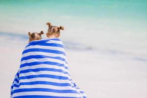 poco carino ragazze avvolto nel asciugamano a tropicale spiaggia. bambini su il spiaggia vacanza foto