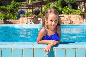 carino contento poco ragazza nel il nuoto piscina guardare a telecamera foto