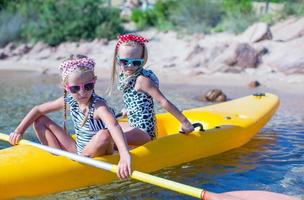 poco adorabile ragazze godendo kayak su giallo kayak nel il chiaro turchese acqua foto