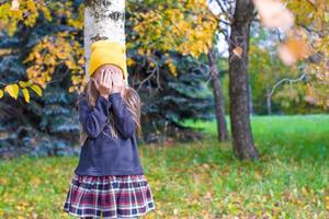 poco ragazza giocando nascondere e cercare nel autunno foresta foto