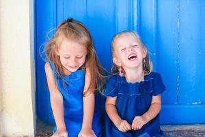ritratto di poco sorridente ragazze seduta vicino vecchio blu porta nel greco villaggio, emporio, santorini foto