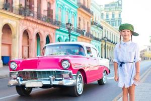 adorabile poco ragazza nel popolare la zona nel vecchio l'Avana, Cuba. ritratto di ragazzo sfondo Vintage ▾ classico americano auto foto