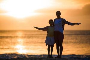 poco ragazza e contento madre silhouette nel il tramonto a il spiaggia foto