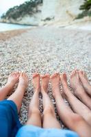 avvicinamento di il piedi di famiglia su il bianca sabbioso spiaggia foto