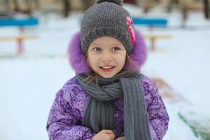 ritratto di poco carino contento ragazza avendo divertimento nel il neve su un' soleggiato inverno giorno foto