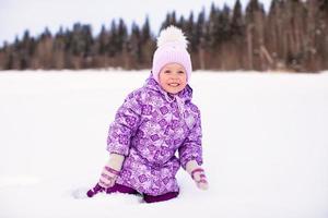 contento poco ragazza avendo divertimento su il neve a inverno soleggiato giorno foto