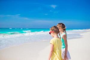poco ragazze avendo divertimento a tropicale spiaggia giocando insieme su il riva del mare foto