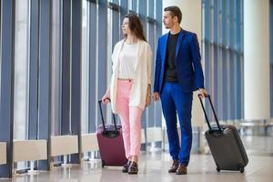 turisti coppia con Bagaglio nel internazionale aeroporto. uomo e donna andando su atterraggio foto