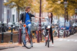 giovane contento caucasico coppia su Bici nel vecchio strade nel amsterdam foto