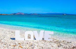 parola amore su tropicale spiaggia sfondo di turchese mare e blu cielo foto