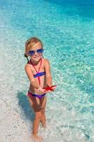 poco adorabile ragazza con mare stella a il tropicale spiaggia foto