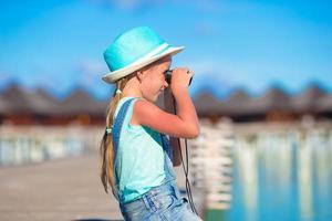 poco ragazza guardare attraverso binocolo nel soleggiato giorno durante estate vacanza foto