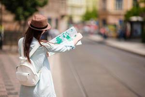 youn ragazza con mappa della città a piedi su europeo strade. viaggio caucasico donna con carta geografica al di fuori durante vacanze nel Europa. foto