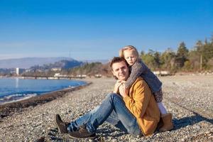 giovane padre e poco ragazza a il spiaggia su un' soleggiato inverno giorno foto