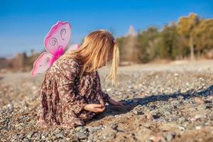 adorabile poco ragazza giocando su il spiaggia nel un' inverno soleggiato giorno foto