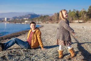 poco ragazza e giovane padre a il spiaggia su un' soleggiato inverno giorno foto