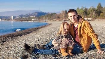 giovane padre e poco ragazza a il spiaggia su un' soleggiato inverno giorno foto