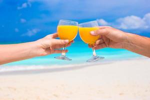 Due mani hold bicchieri con arancia succo sfondo blu cielo foto