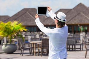 giovane uomo rendere un' foto su tavoletta computer a tropicale spiaggia